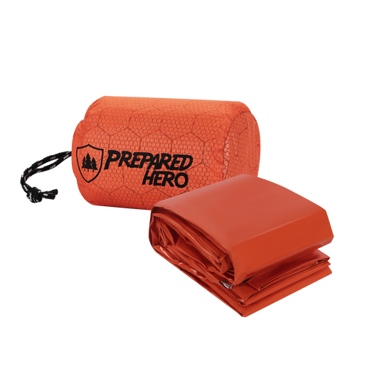 Hero Survival Bag in its orange drawstring stuff sack, with the folded sleeping bag beside it